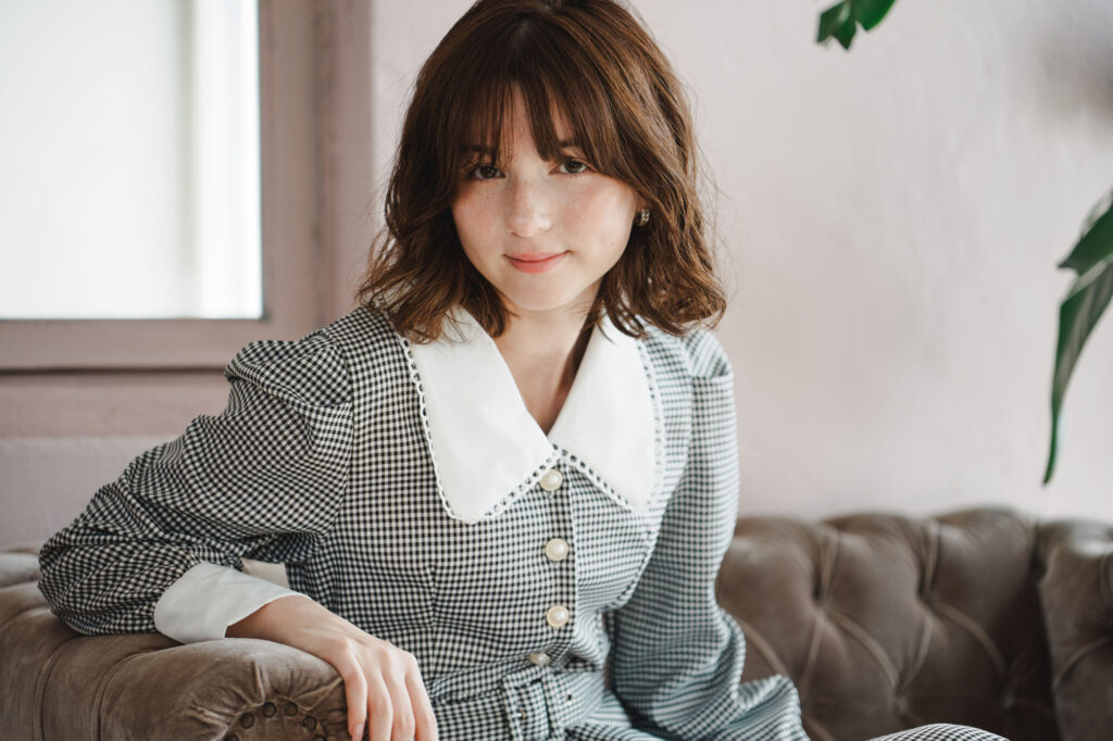 An image of a woman sitting on a sofa, showcasing the Tamron 35-100mm F/2.8 Di III VXD lens.