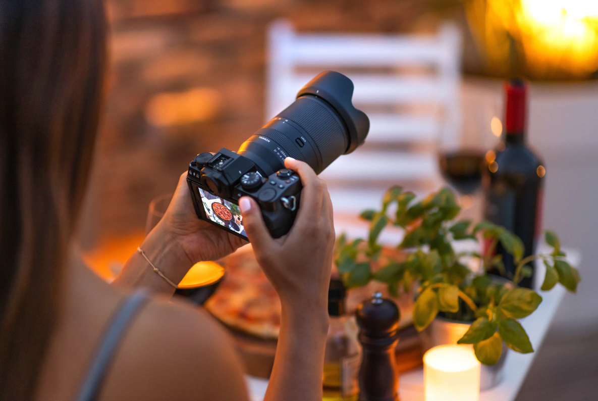 Photographer using Tamron lens to capture outdoor scene at sunset.