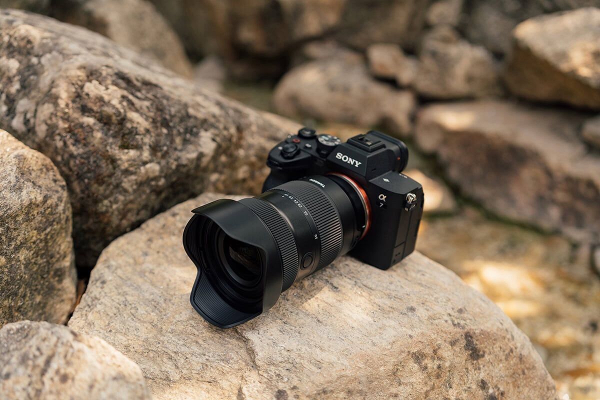 Sony camera with Tamron lens on rocky terrain in nature.