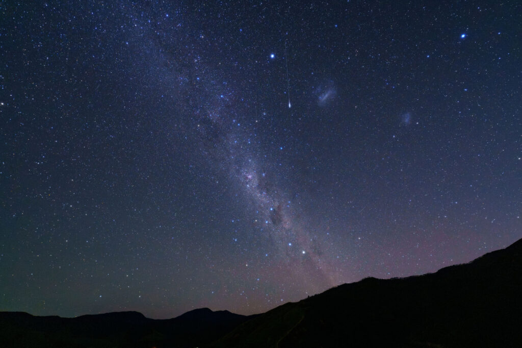 Night sky with stars and the Milky Way over a mountain landscape.