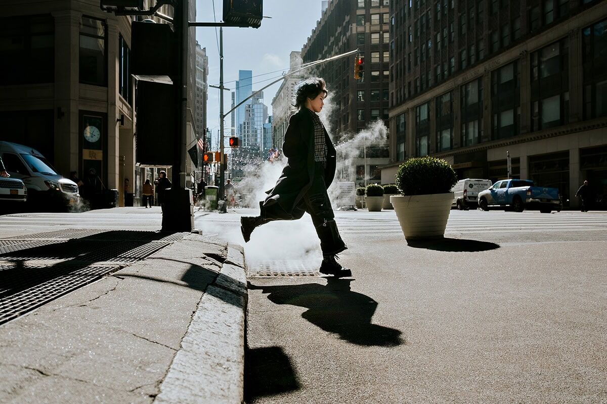 Woman crossing city street using Tamron wide angle lens.