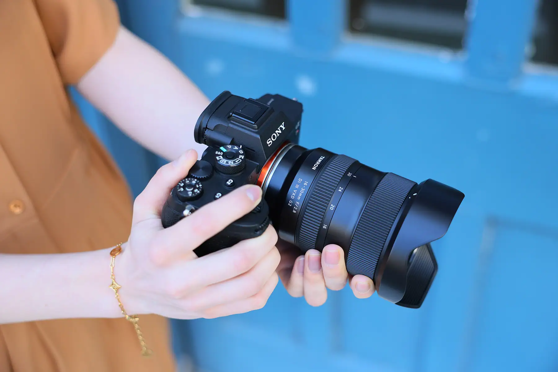 Person holding Sony camera with Tamron lens attached for wide-angle shots.