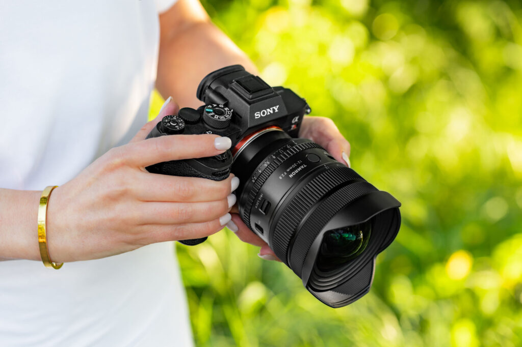Tamron Lens on Sony Camera Person holding Sony camera with Tamron lens outdoors.